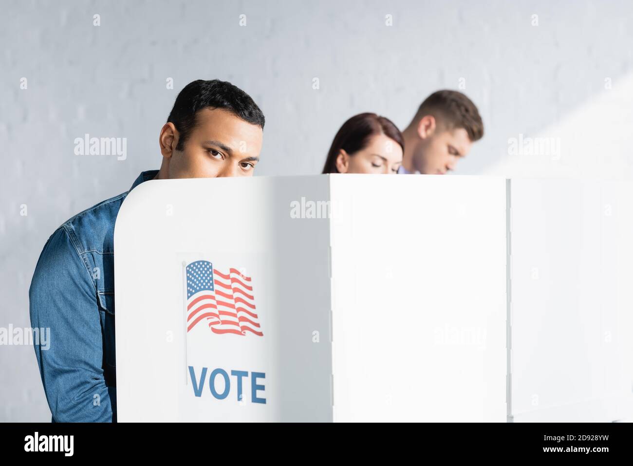 indian man looking at camera from polling booth near multicultural electors on blurred background Stock Photo