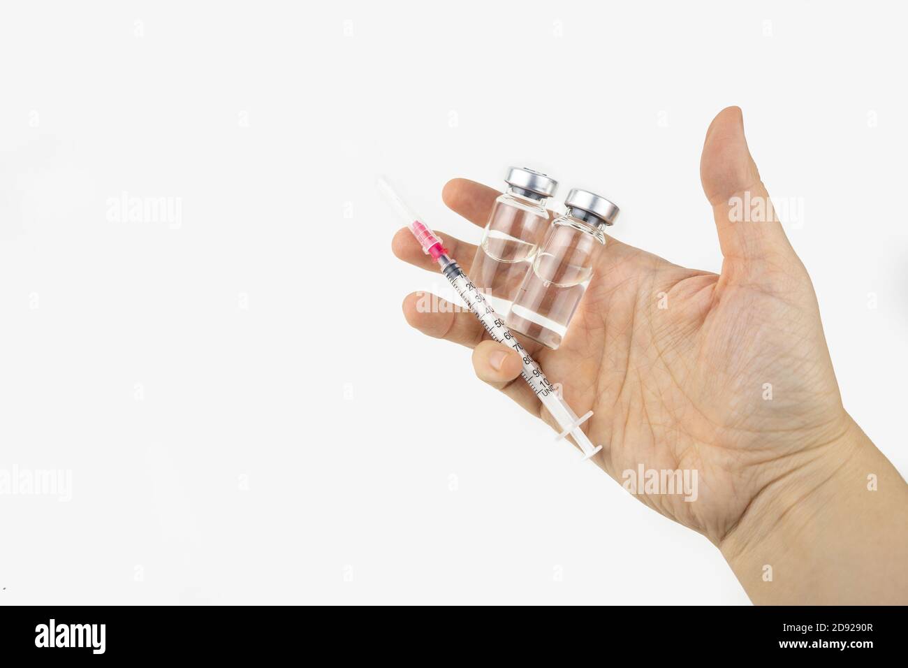 Two vials with medicine and syringe in a hand for injection treatment ...