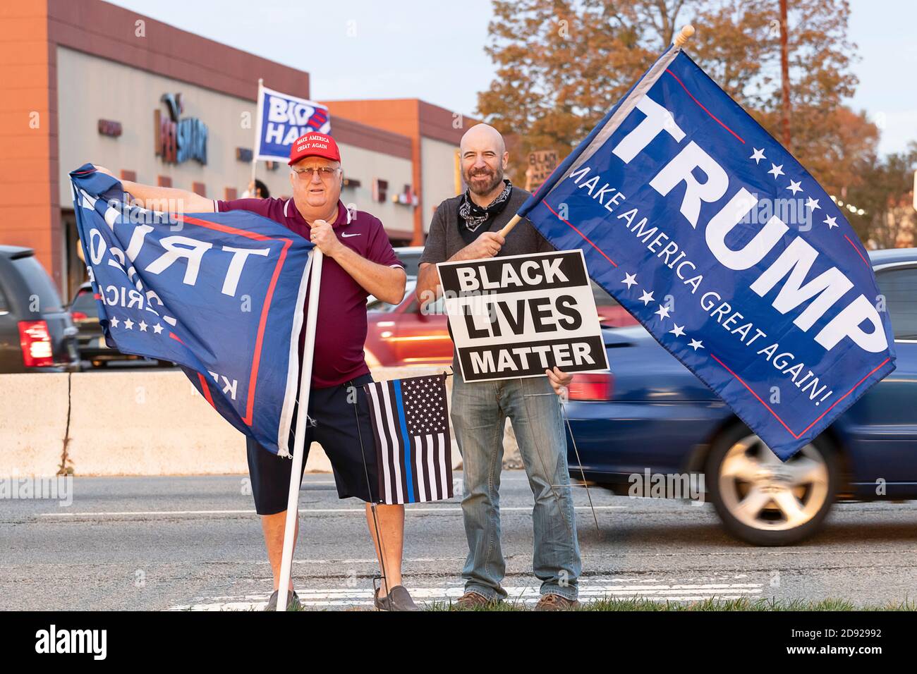 Donald Trump supporters holding signs and flags at local sidewalk rally, including 'Black Lives Matter' sign. Stock Photo