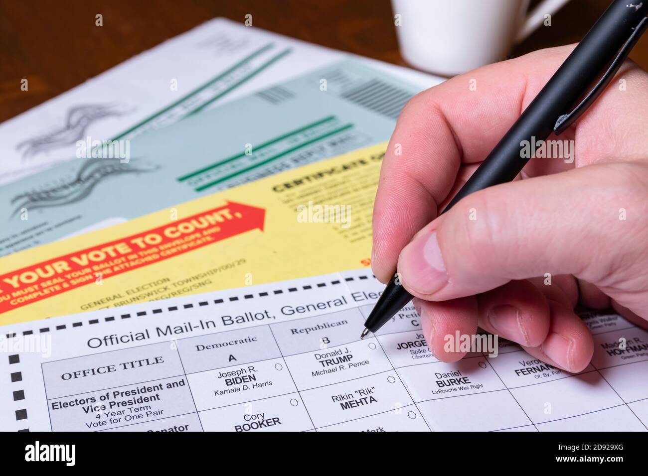 Hand holding pen, preparing to fill out official mail-in ballot for 2020 US General Election. Stock Photo