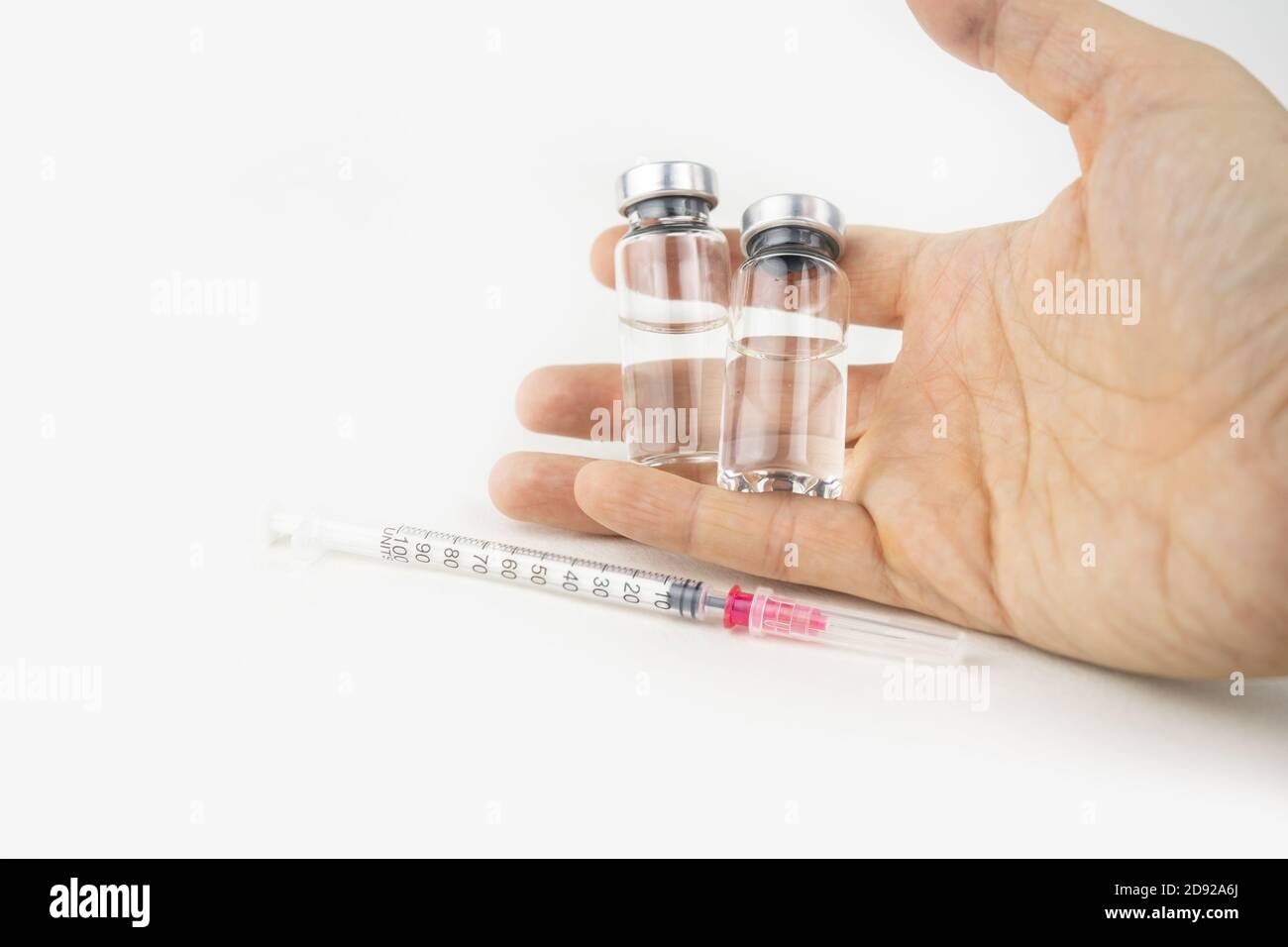 Two vials with medicine and syringe in a hand for injection treatment ...