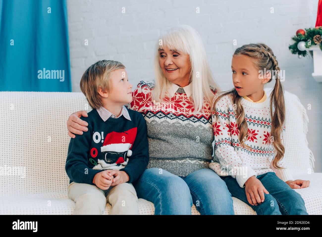 smiling senior woman talking to grandchildren while sitting on sofa together Stock Photo