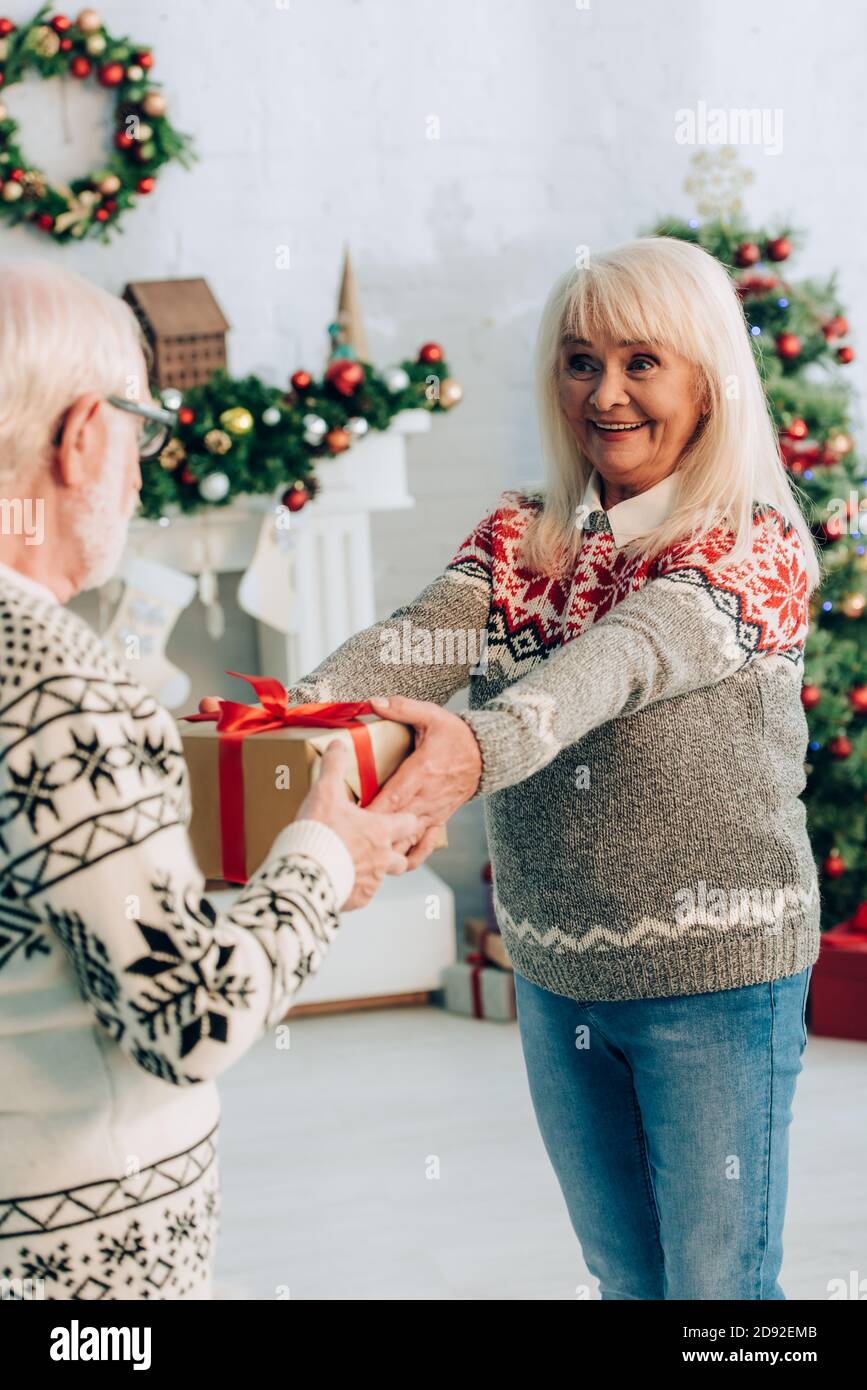 Ahuevoo Senor Gift selective focus of cheerful senior woman presenting christmas gift to ...