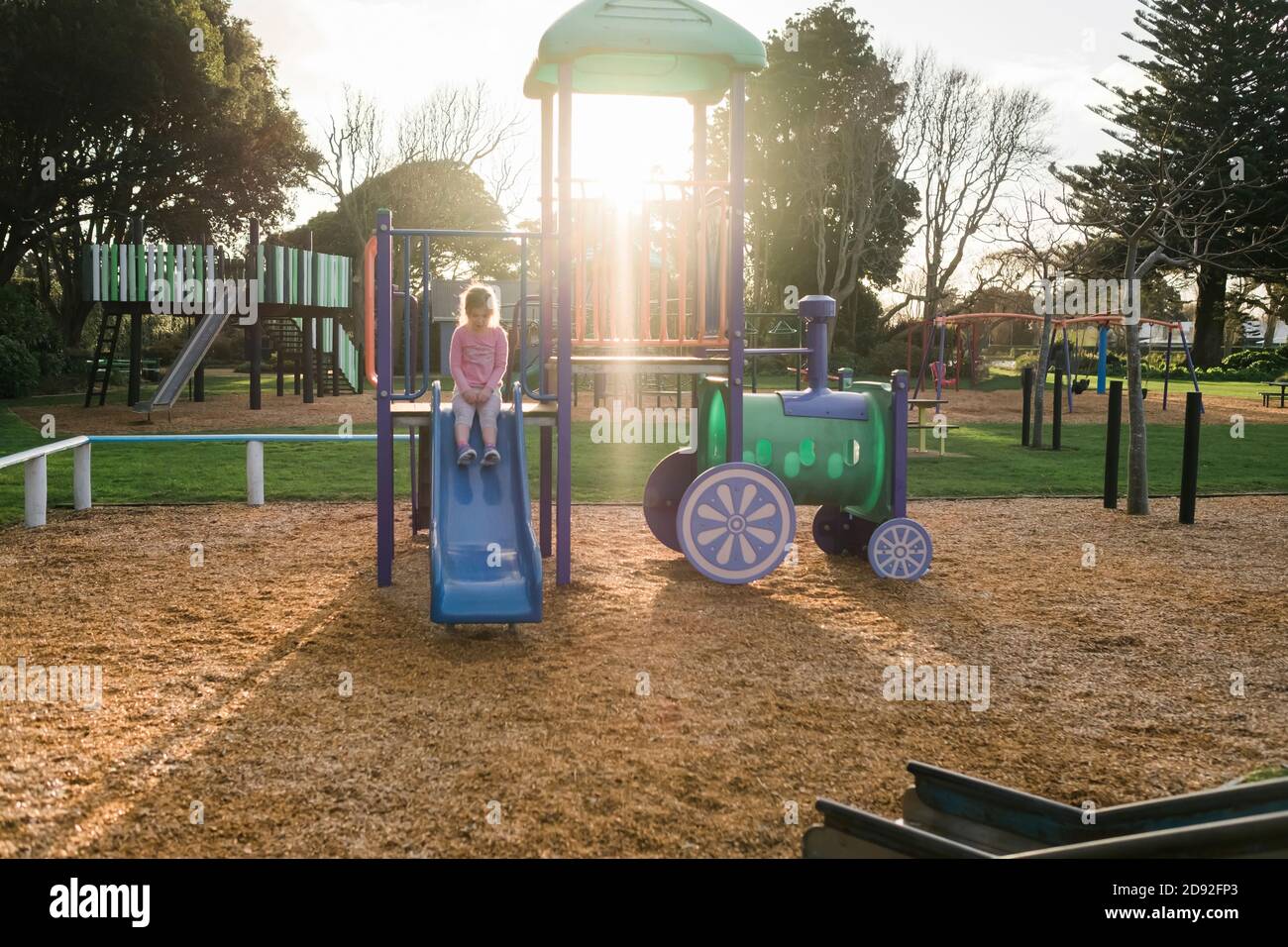 Young girl sitting on slide at a playground Stock Photo - Alamy