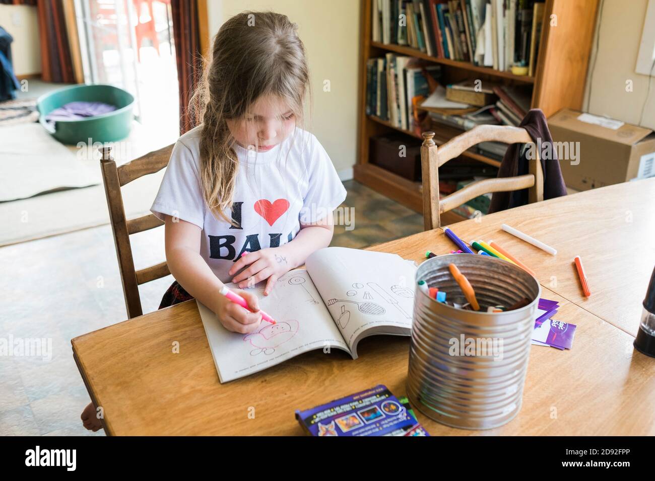 Young girl sitting at a table coloring and drawing Stock Photo - Alamy