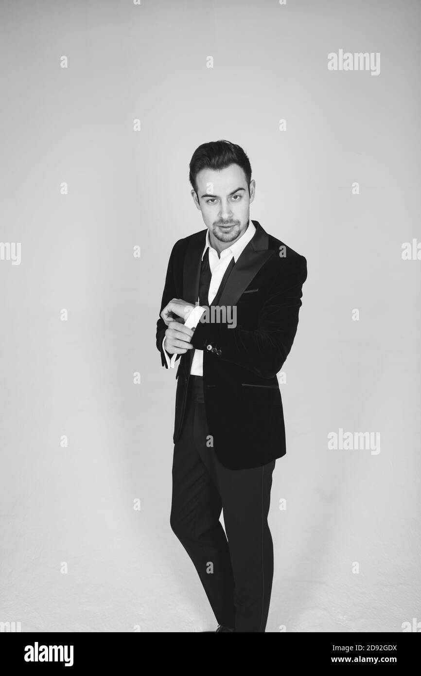 Studio portrait of a young caucasian man in a tuxedo, looking at the camera, standing against plain studio background Stock Photo