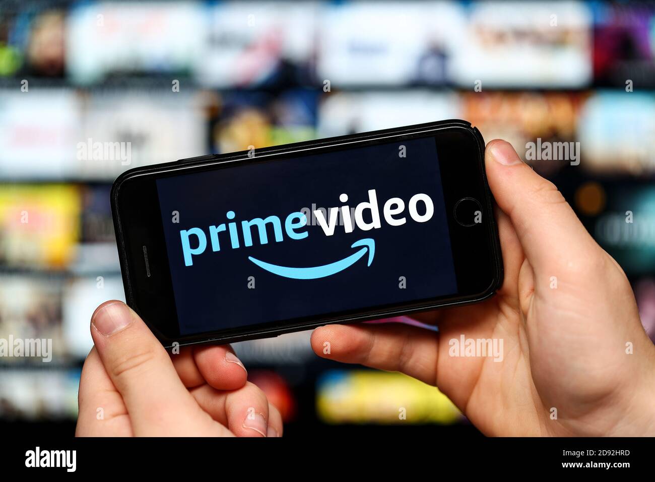 A teenager watching Amazon Prime Video on a mobile phone and computer Stock Photo