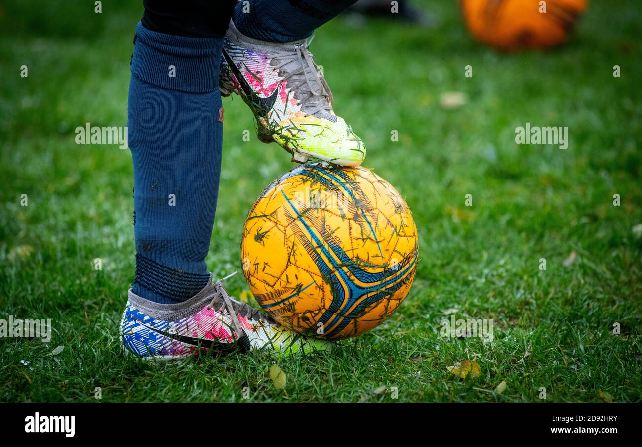A young boy with his foot on a football during a youth football match in the UK Stock Photo