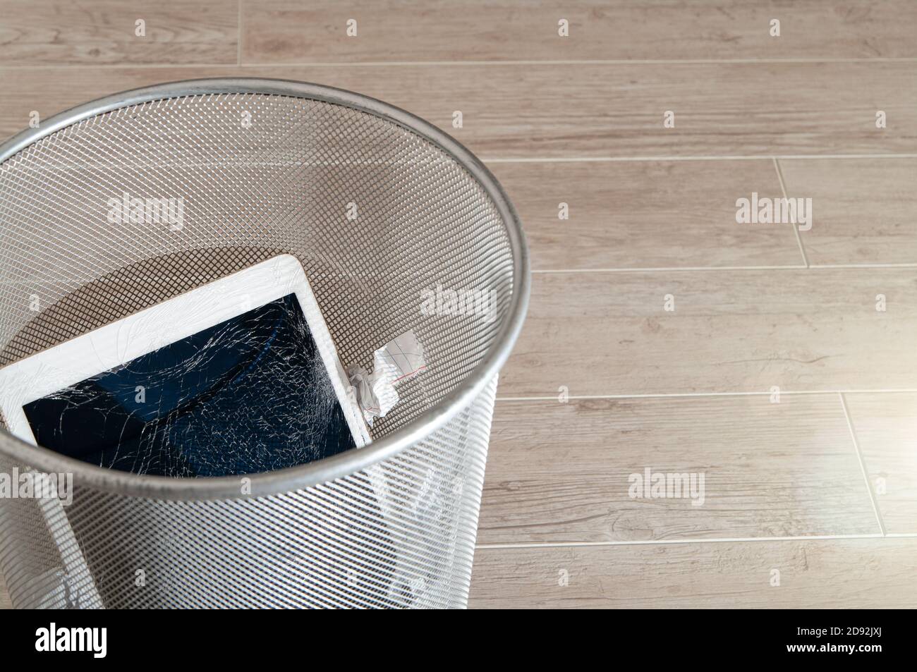Modern tablet with highly broken screen in the litter bin. Stock Photo