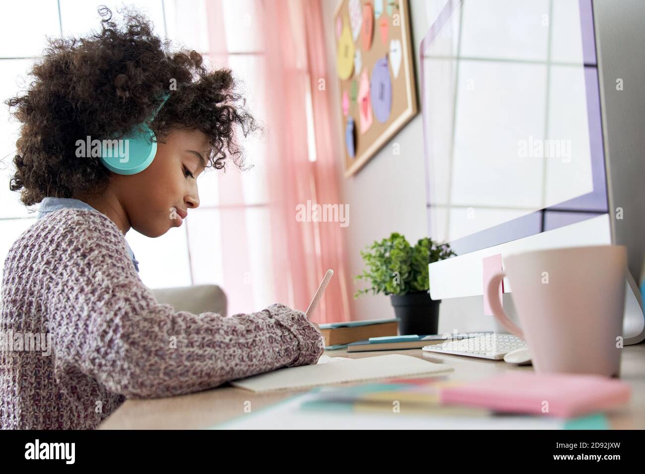 African school kid girl wearing headphones virtual distance learning at home. Stock Photo