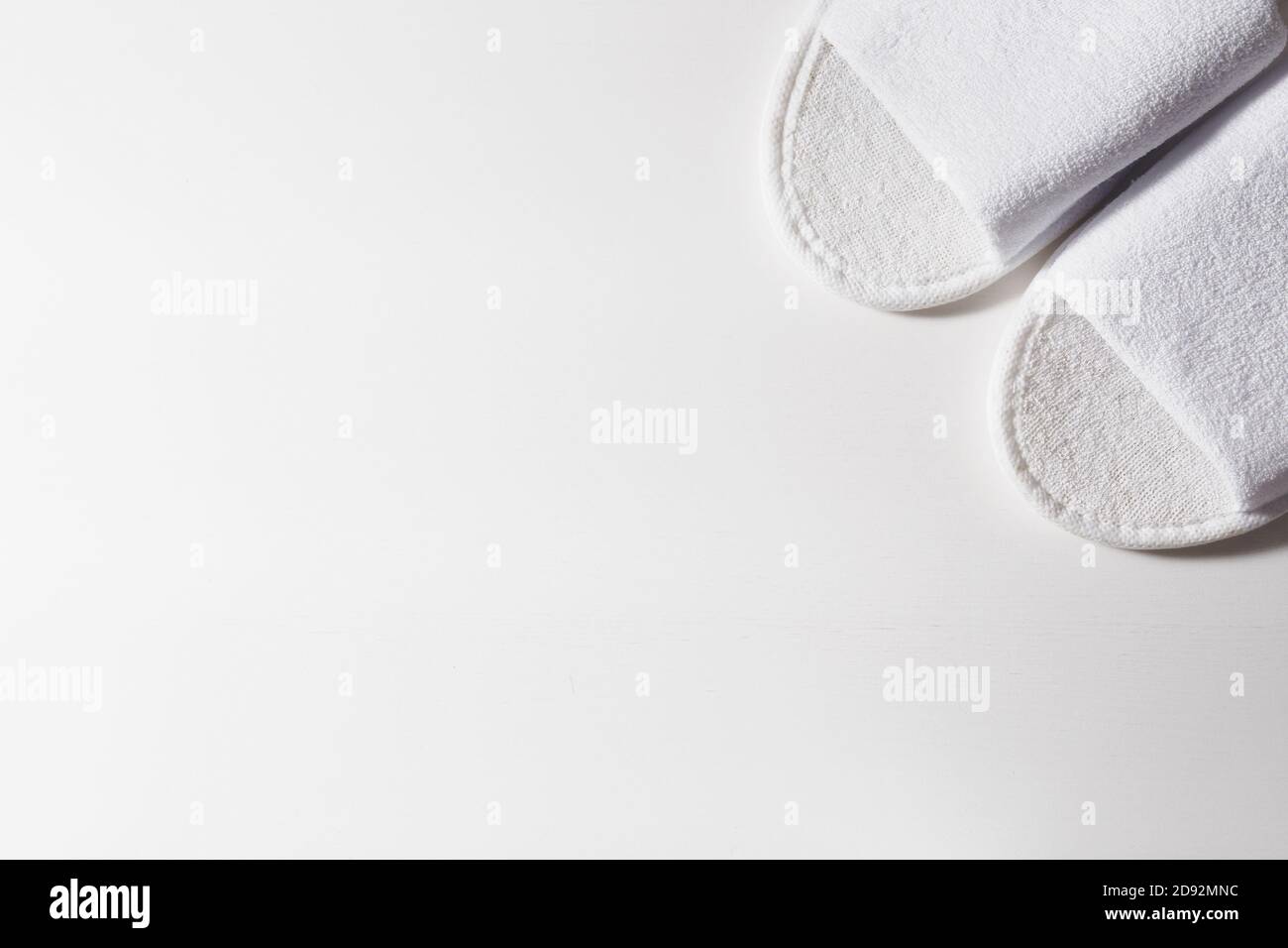 Top view of white slippers on a white wooden background. Copy space for text. Stock Photo
