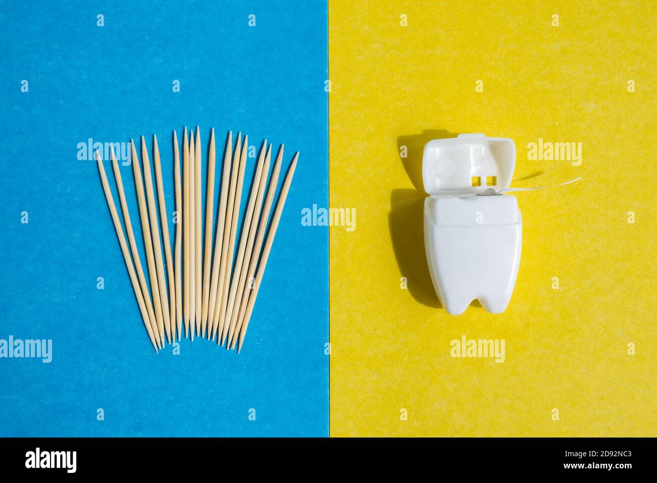 toothpicks on blue background and dental floss in white container on yellow backdrop, top view Stock Photo