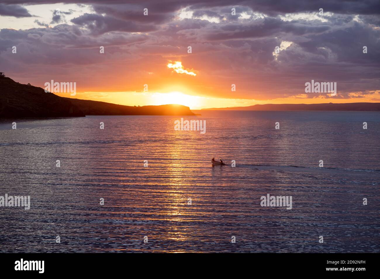 Kea, Tzia island, destination Greece. Sunset, sunrise orange through clouds over Mediterranean sea. The sun reflects on the water,  the speedboat sail Stock Photo