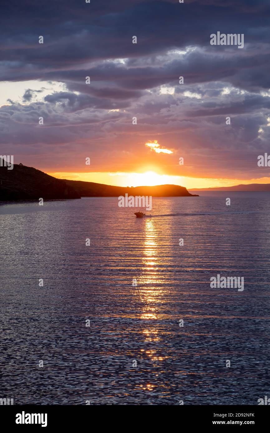 Kea, Tzia island, destination Greece. Sunset, sunrise orange through clouds over Mediterranean sea. The sun reflects on the water. Vertical photo. Stock Photo
