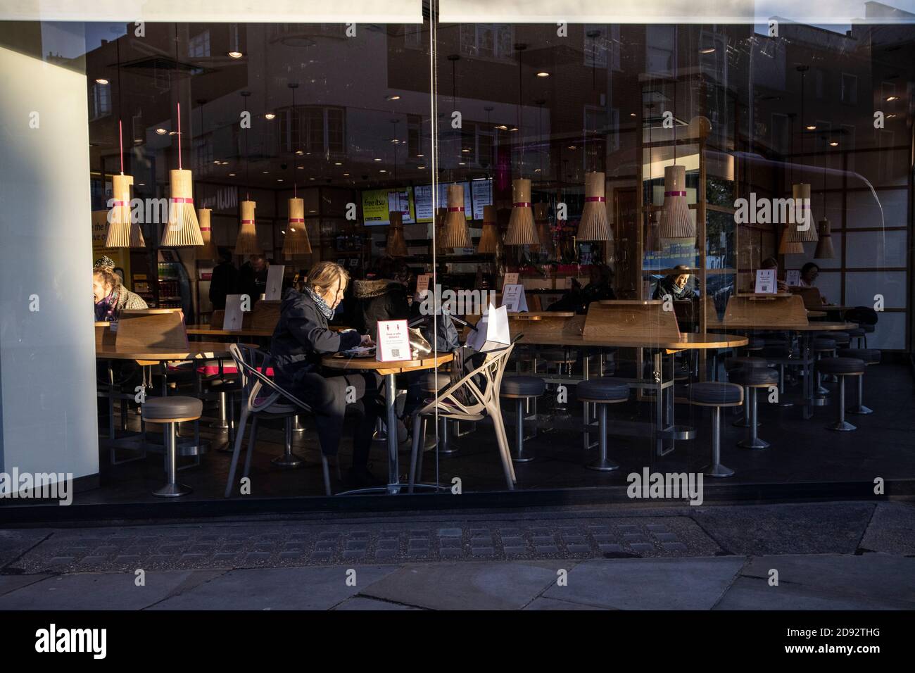 A woman eats alone in an ITSU restaurant on one of the last days before the latest 'Long Lockdown' restrictions are enforced closing restaurants, UK. Stock Photo