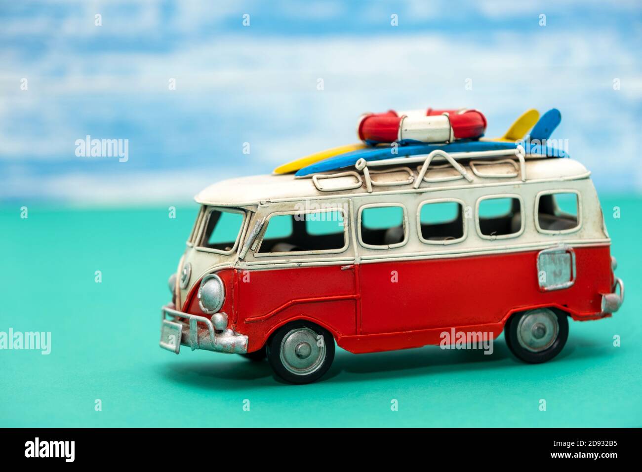 Vintage toy VW minibus with surfboards in front of a blurred background. Stock Photo