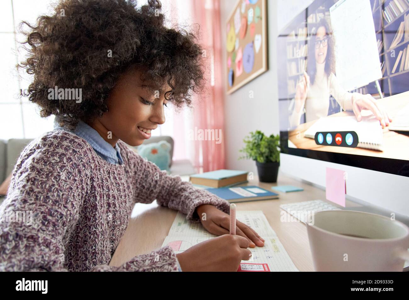 Happy african school child girl online learning with virtual tutor at home. Stock Photo