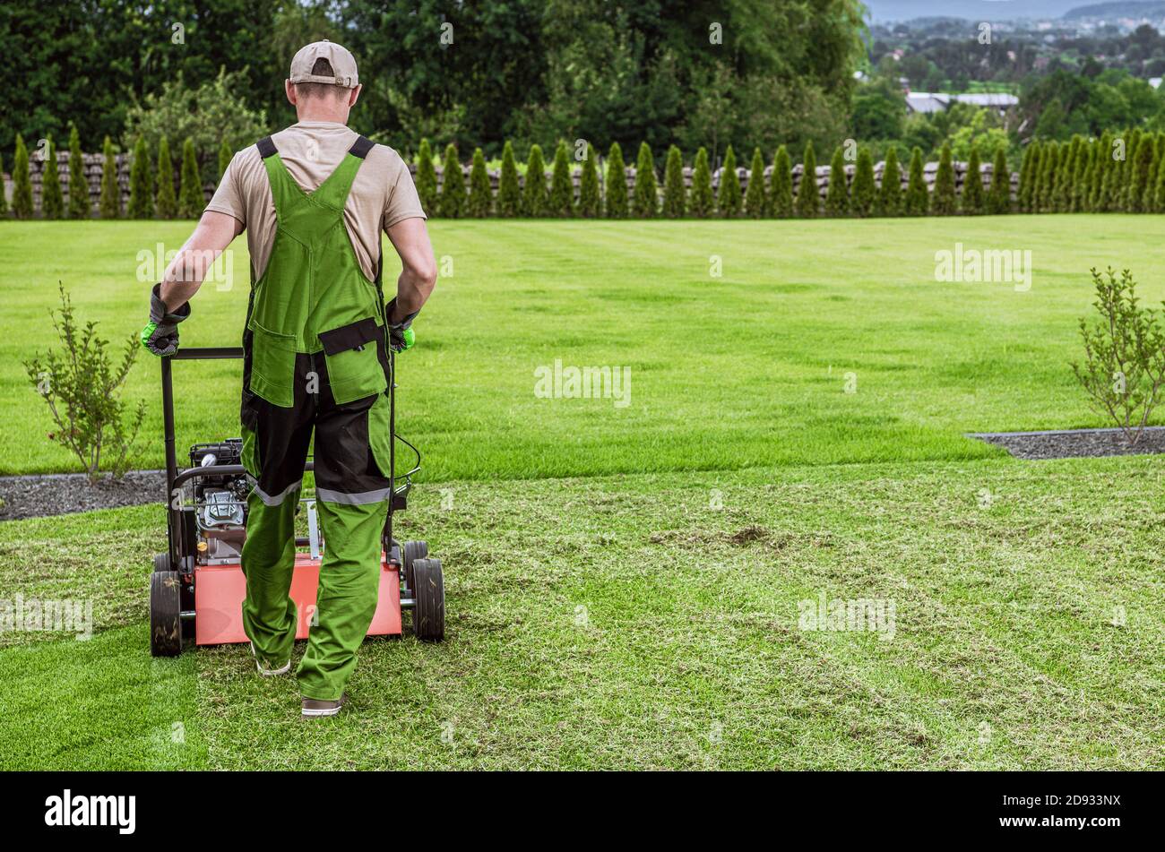 Caucasian Gardener in His 40s and His Powerful Gasoline Lawn Aerator Job For Controlling Lawn Thatch, And Reducing Soil Compaction. Garden Technologie Stock Photo