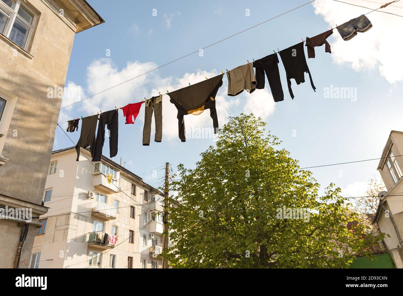 Pure linen is dried on the street. Clothes hanging to dry on the rope. Laundry hanging between houses Stock Photo