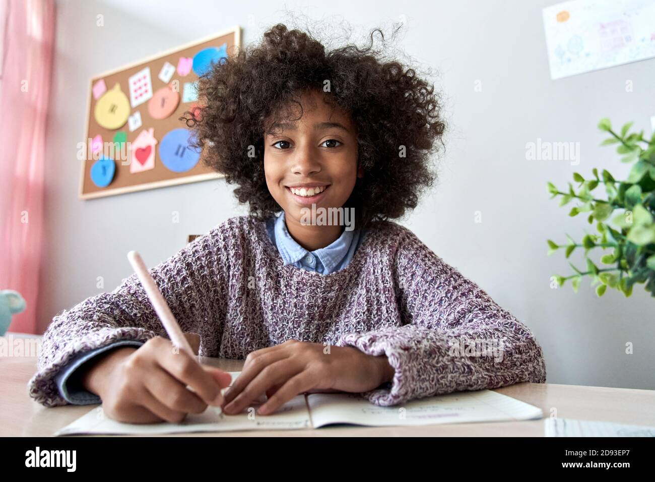 Happy african kid girl looking at web cam remote learning online, headshot. Stock Photo