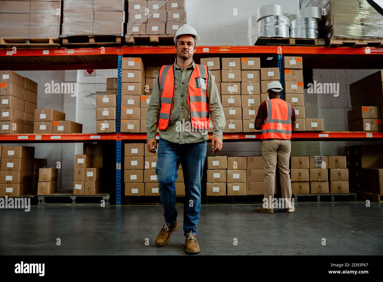 Handsome factory worker wearing overalls walking around warehouse  Stock Photo
