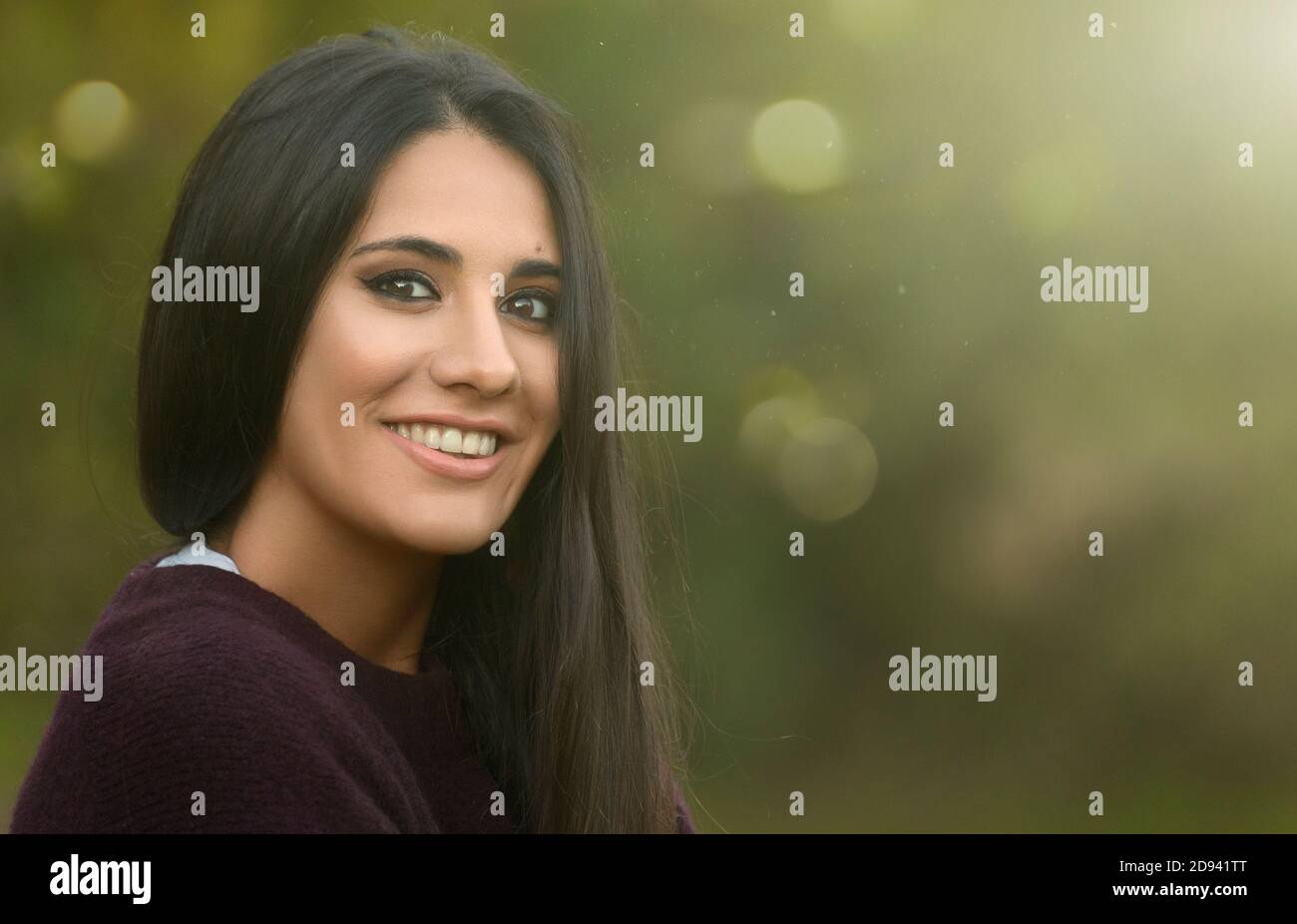 Young happy woman smiling at camera in a green nature background Stock Photo
