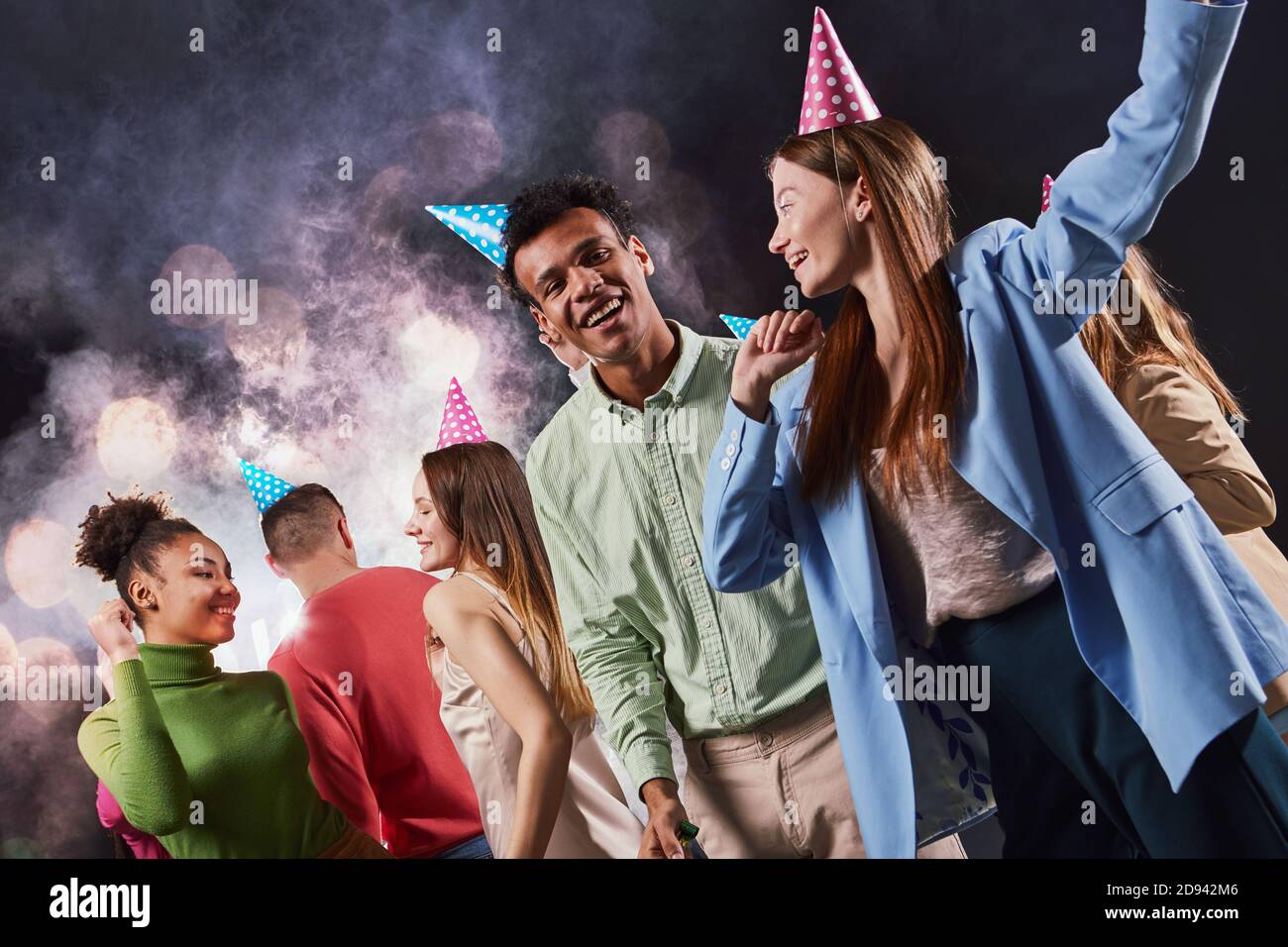 Group of young happy multiracial people wearing birthday hats laughing and having fun, party and celebration concept Stock Photo