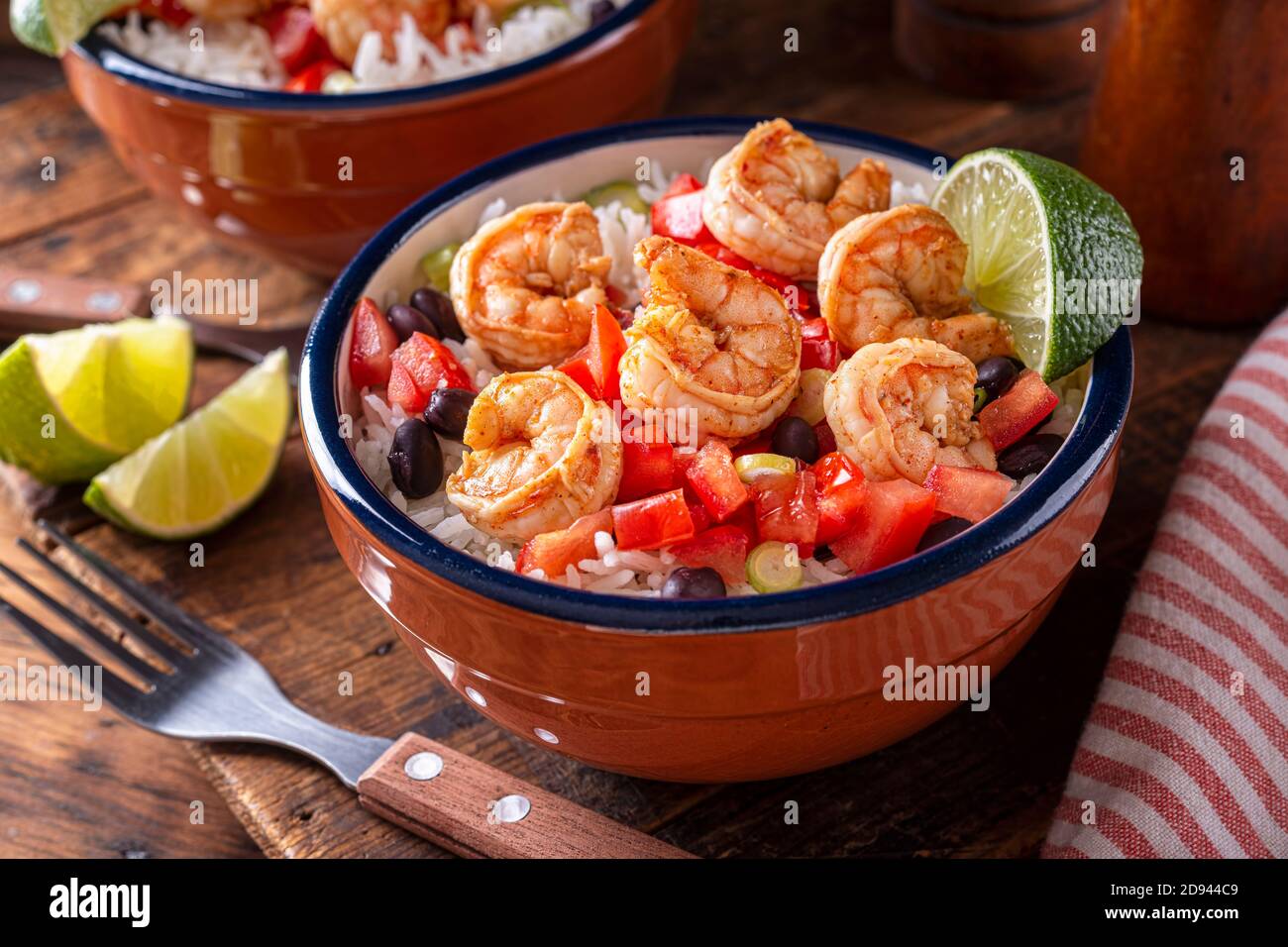 A delicious chili lime shrimp bowl with tomato, cilantro, black beans and rice. Stock Photo