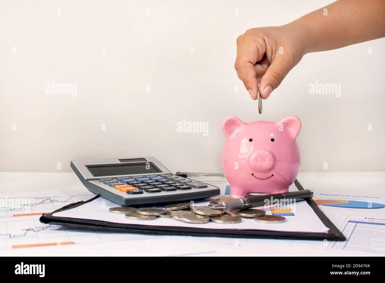 Hand holding a coin to put a piggy bank to save money for sustainable