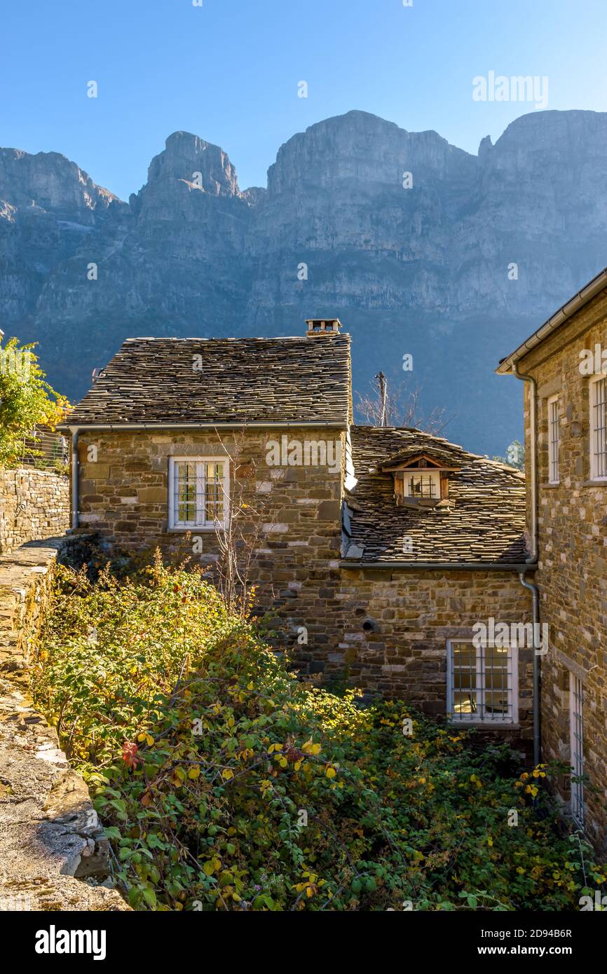 Traditional architecture with  narrow  stone street  and  astraka mountain as background during  fall season in the village Papigo in zagori Greece Stock Photo