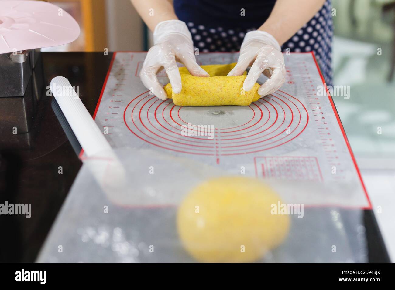 Womens hands roll out the pumpkin bread dough on kitchen table. Stock Photo