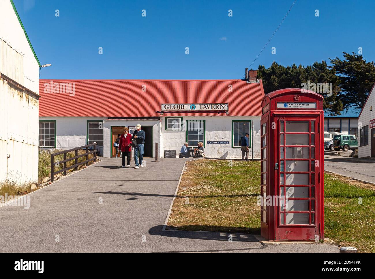 Stanley, Falkland Islands, UK - December 15, 2008: Globe Tavern as white building with red roof under full blue sky, with classic English telephone bo Stock Photo