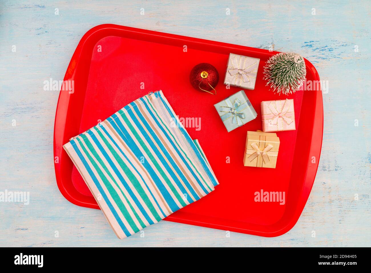 Christmas composition. Christmas gift boxes. Red plastic dining tray on the table. Stock Photo