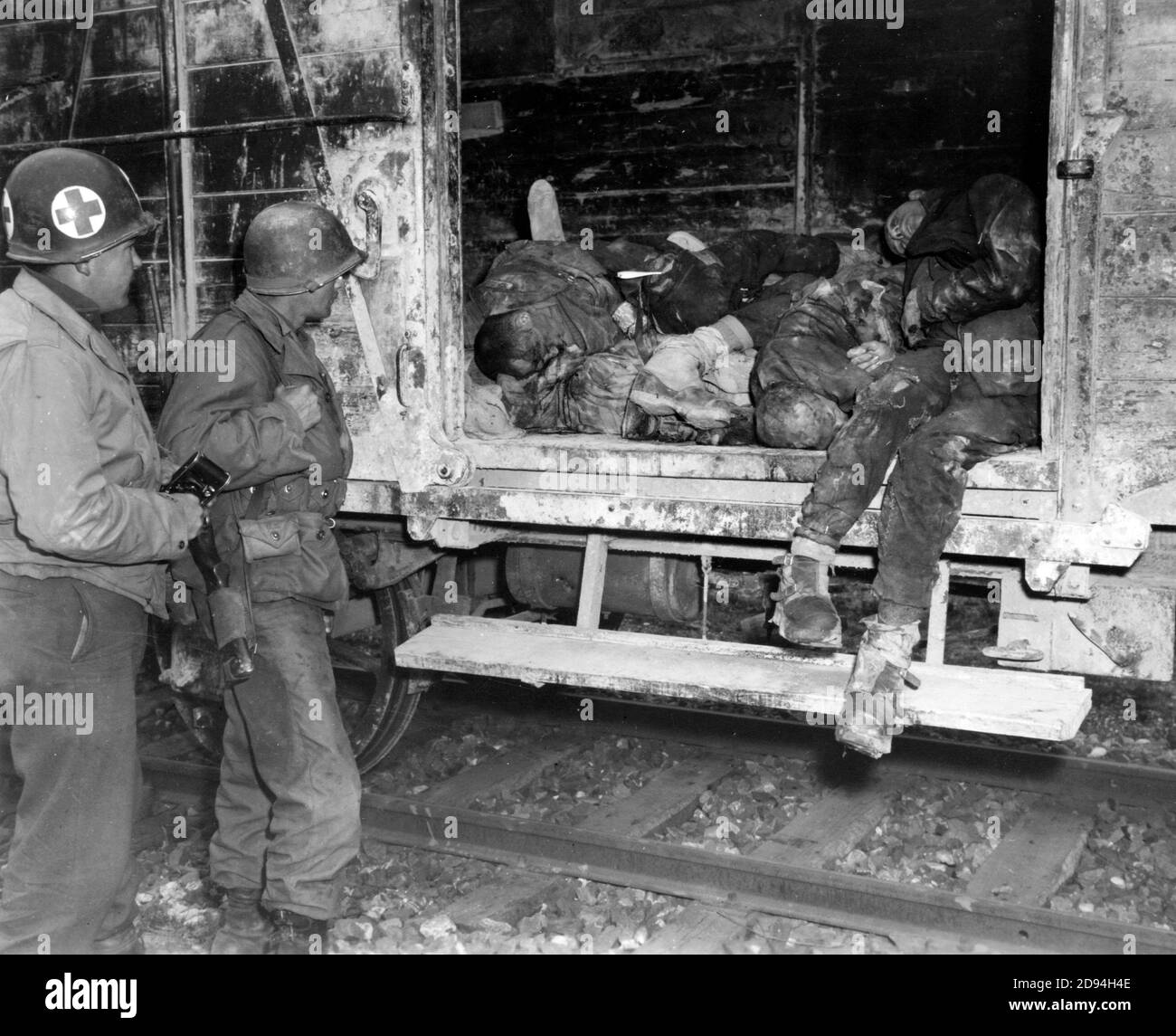 Two U.S. soldiers looking at dead prisoners on railroad train at unidentified concentration camp in Germany, April 1945 Stock Photo