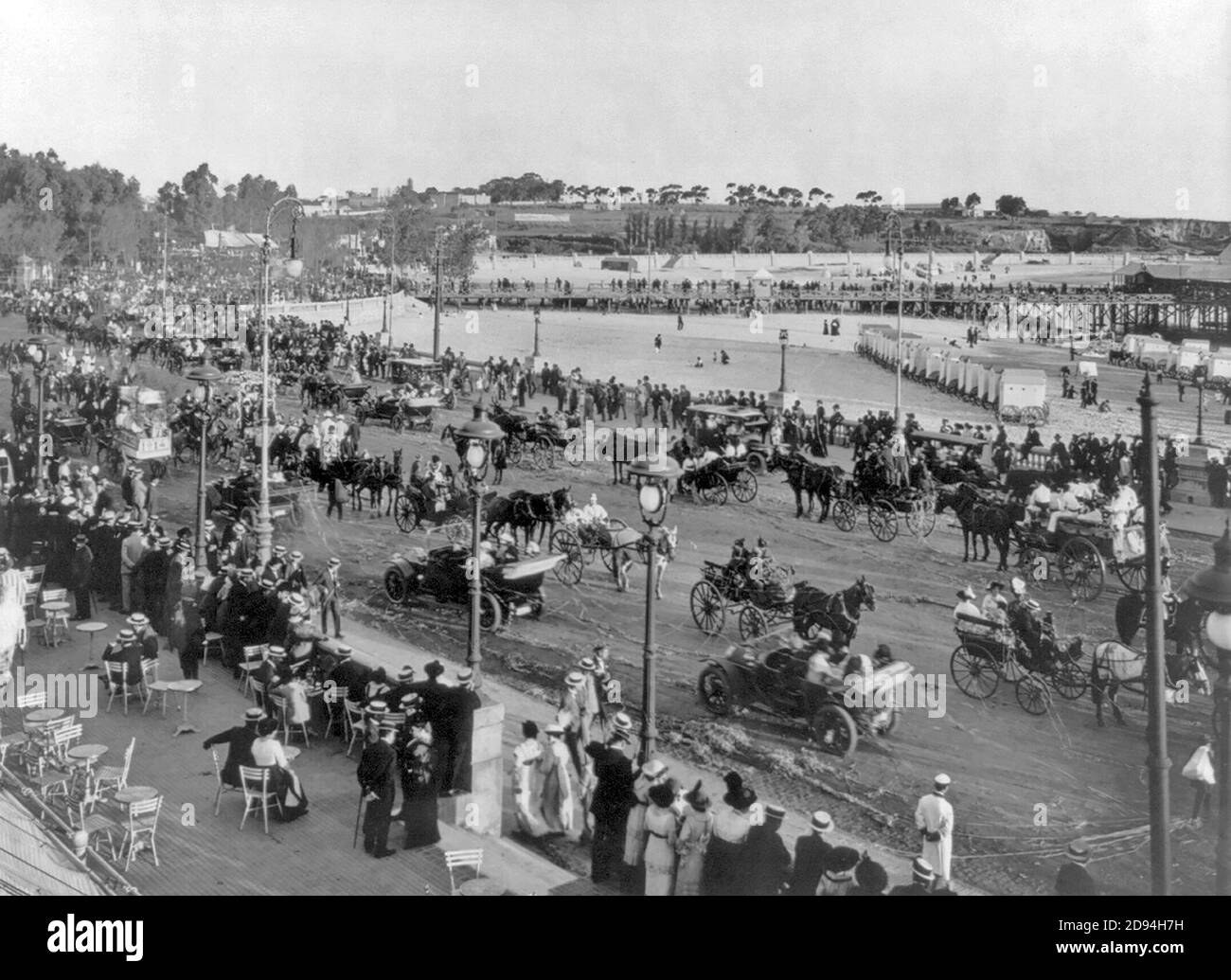 Scene at 1914 festival; parade of autos and carriages along beachfront boulevard; rows of 4-wheeled bathhouses on beach. Montevideo, Uruguay Stock Photo