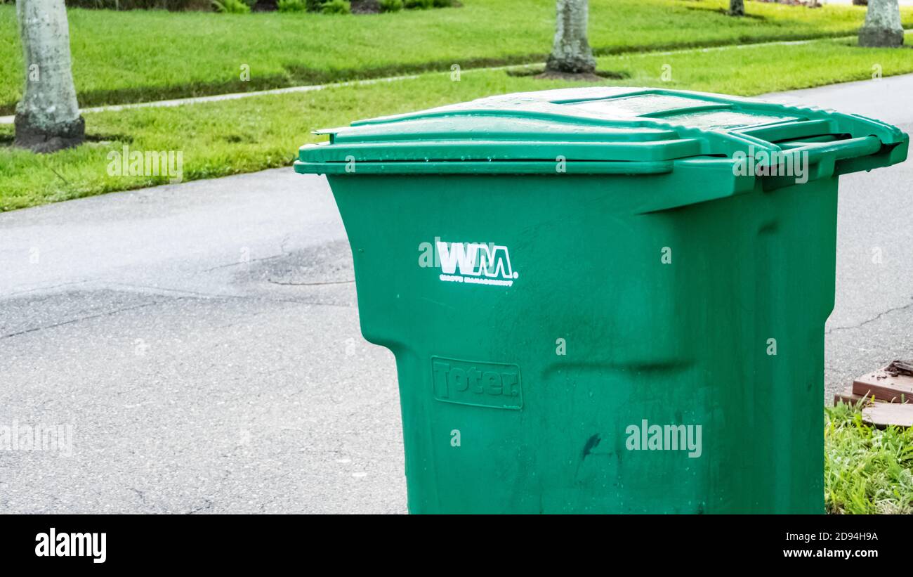 Green and yellow waste management garbage cans at the curb for trash