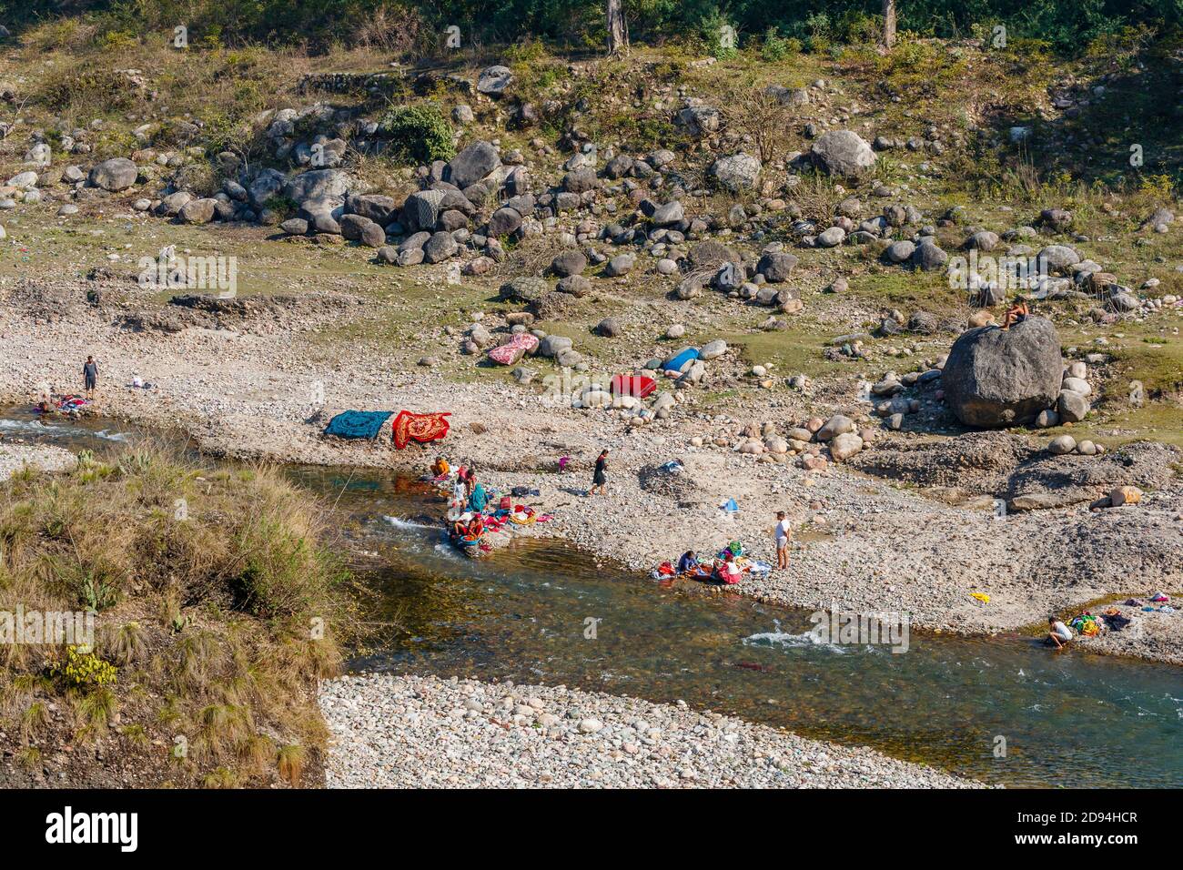 Local people washing and sun drying clothes on the side of a river in Kaswara, near Old Kangra and Kangra Fort in Himachal Pradesh, north India Stock Photo