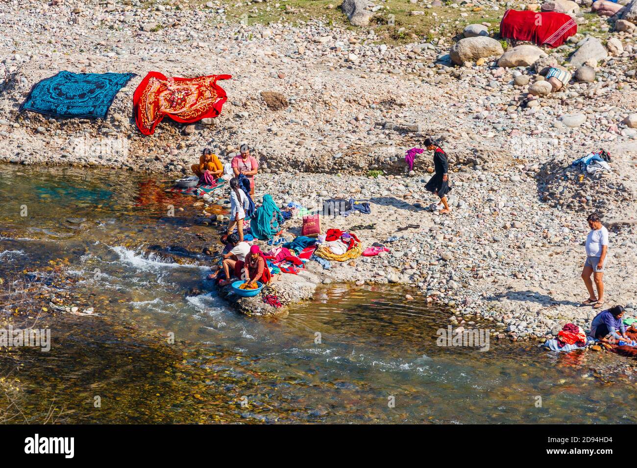 Local people washing and sun drying clothes on the side of a river in Kaswara, near Old Kangra and Kangra Fort in Himachal Pradesh, north India Stock Photo