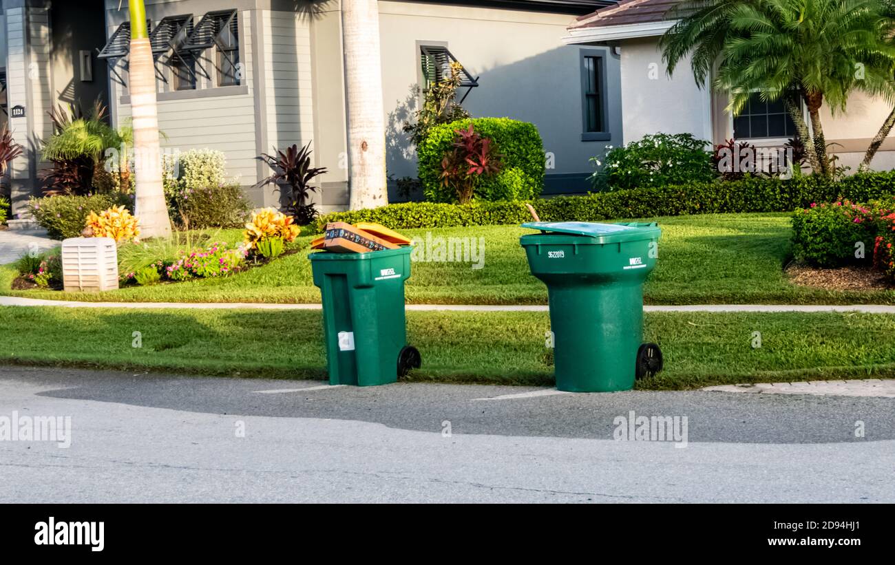 Green and yellow waste management garbage cans at the curb for trash