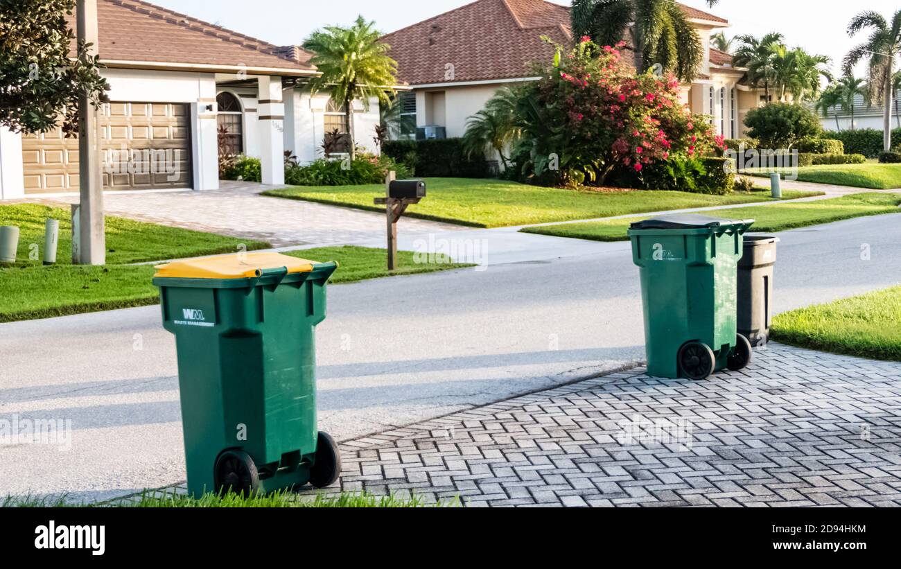 Green and yellow waste management garbage cans at the curb for trash