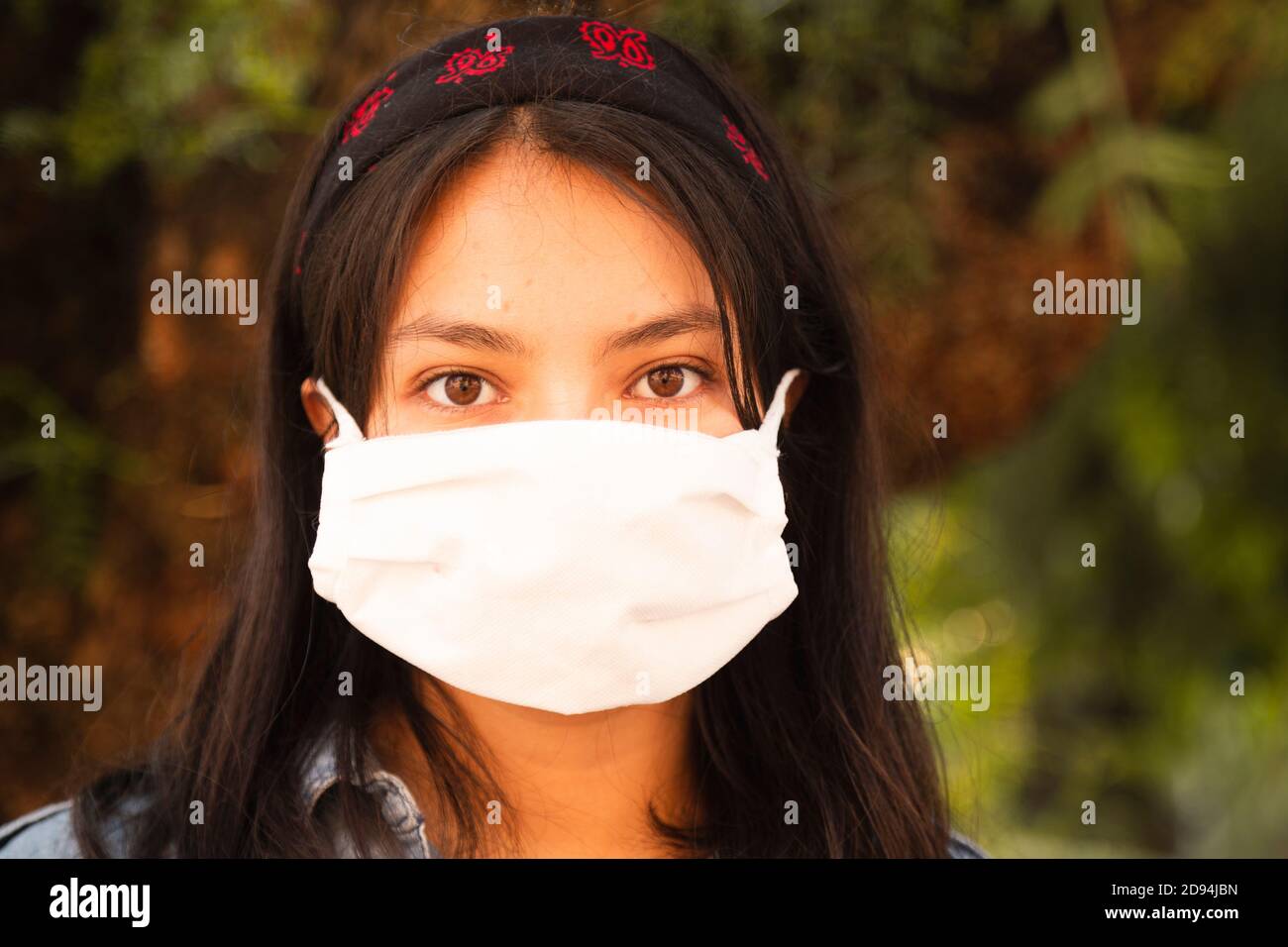 Hispanic woman wearing face mask on street near trees and nature Stock ...