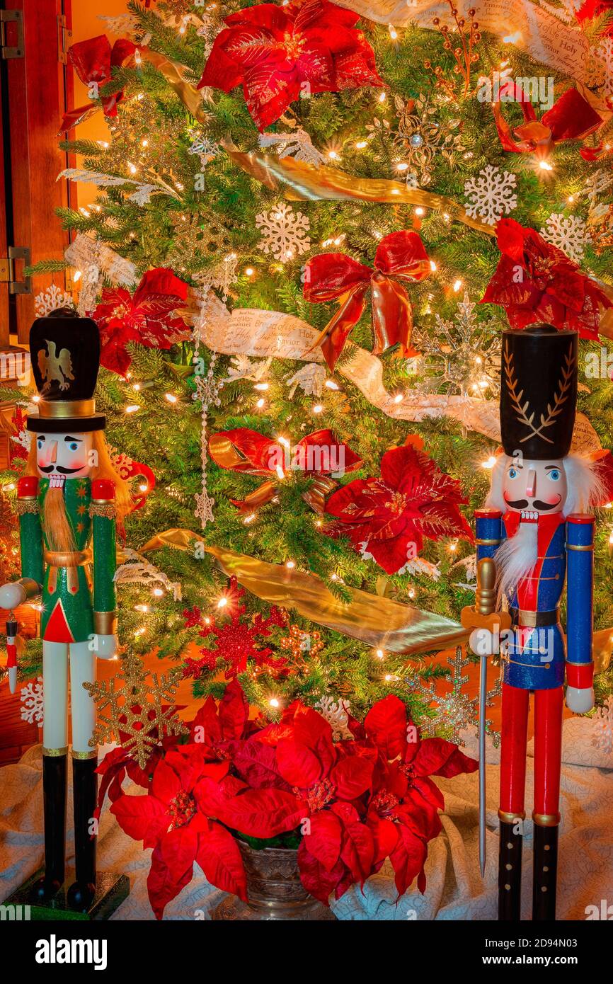 Christmas tree is decorated with snowflakes and ribbon and has  two large nutcrackers on guard below. Stock Photo