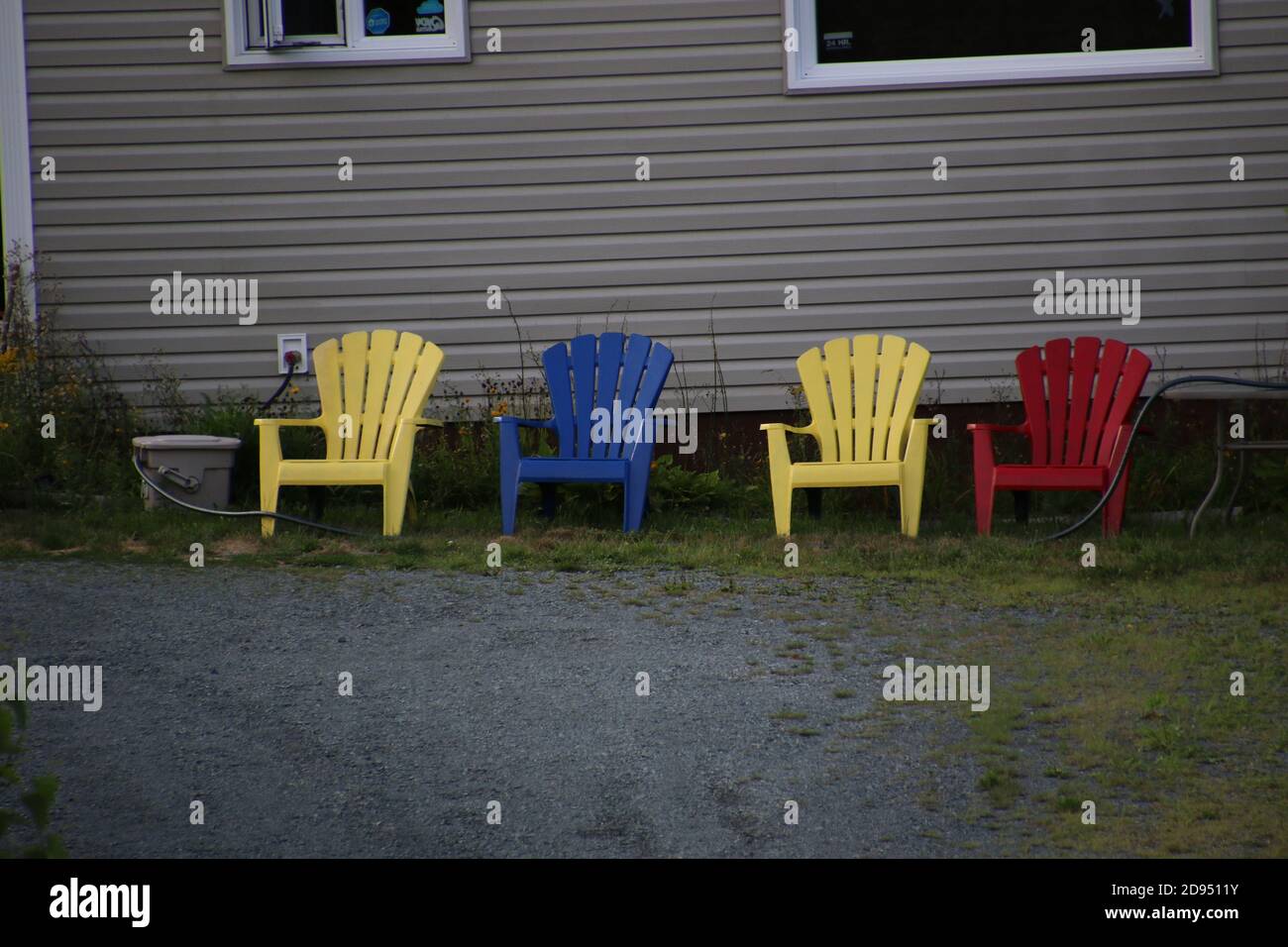 Four colorful lawn chairs sitting outside a house waiting to be used Stock Photo