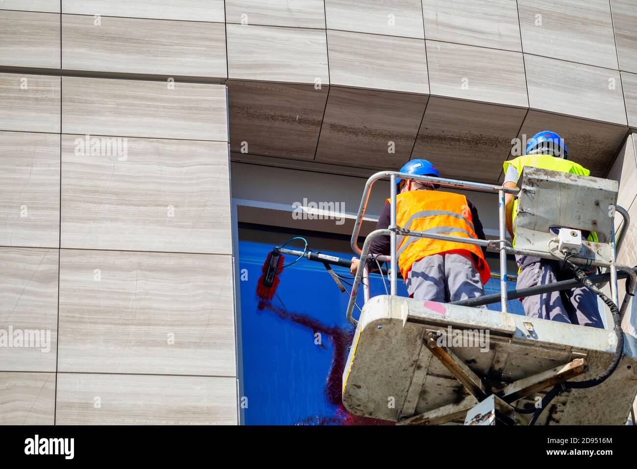 Two window cleaners working in elevated work platform, cleaning