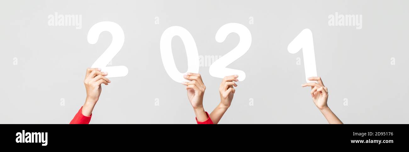 Hands holding and raising nubers 2021 on light gray banner background for new year concepts Stock Photo