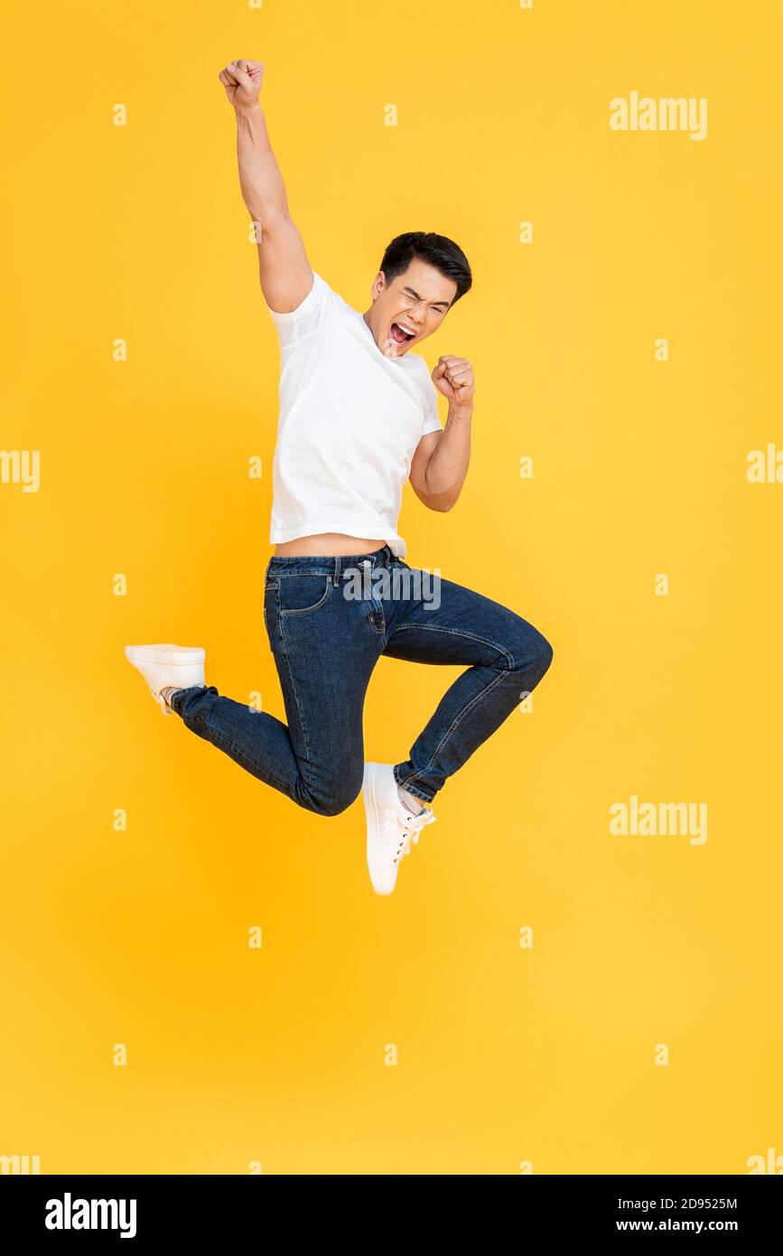 Young energetic Asian man jumping and raising his fist isolated on