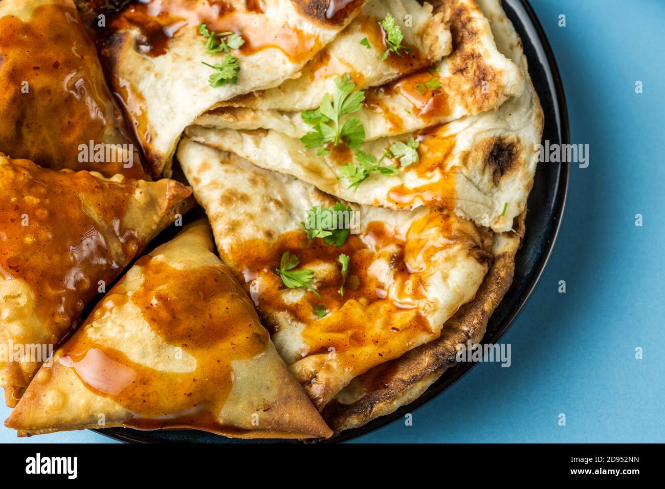 Indian snacks samosa garlic naan bread on wooden table Stock Photo