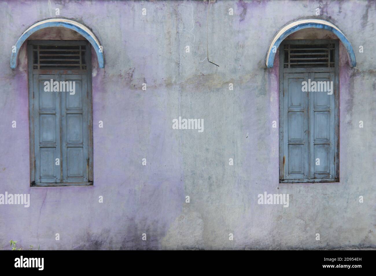 old house building with two wooden windows and a broken wall. old house in rural indonesia. mossy wall texture for the background Stock Photo