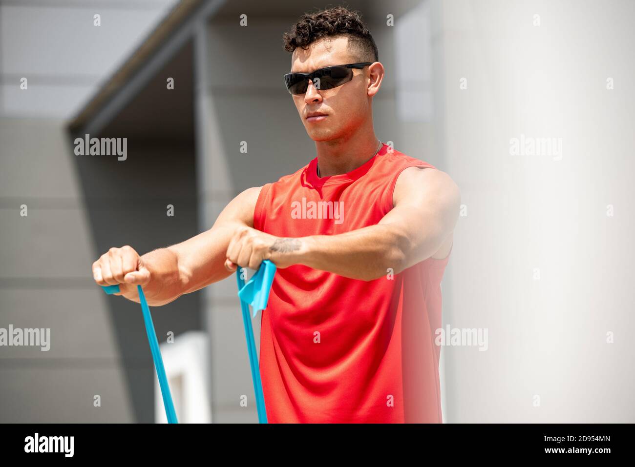 Handsome sports man doing shoulder front raise morning exercise with resistance band outdoors Stock Photo