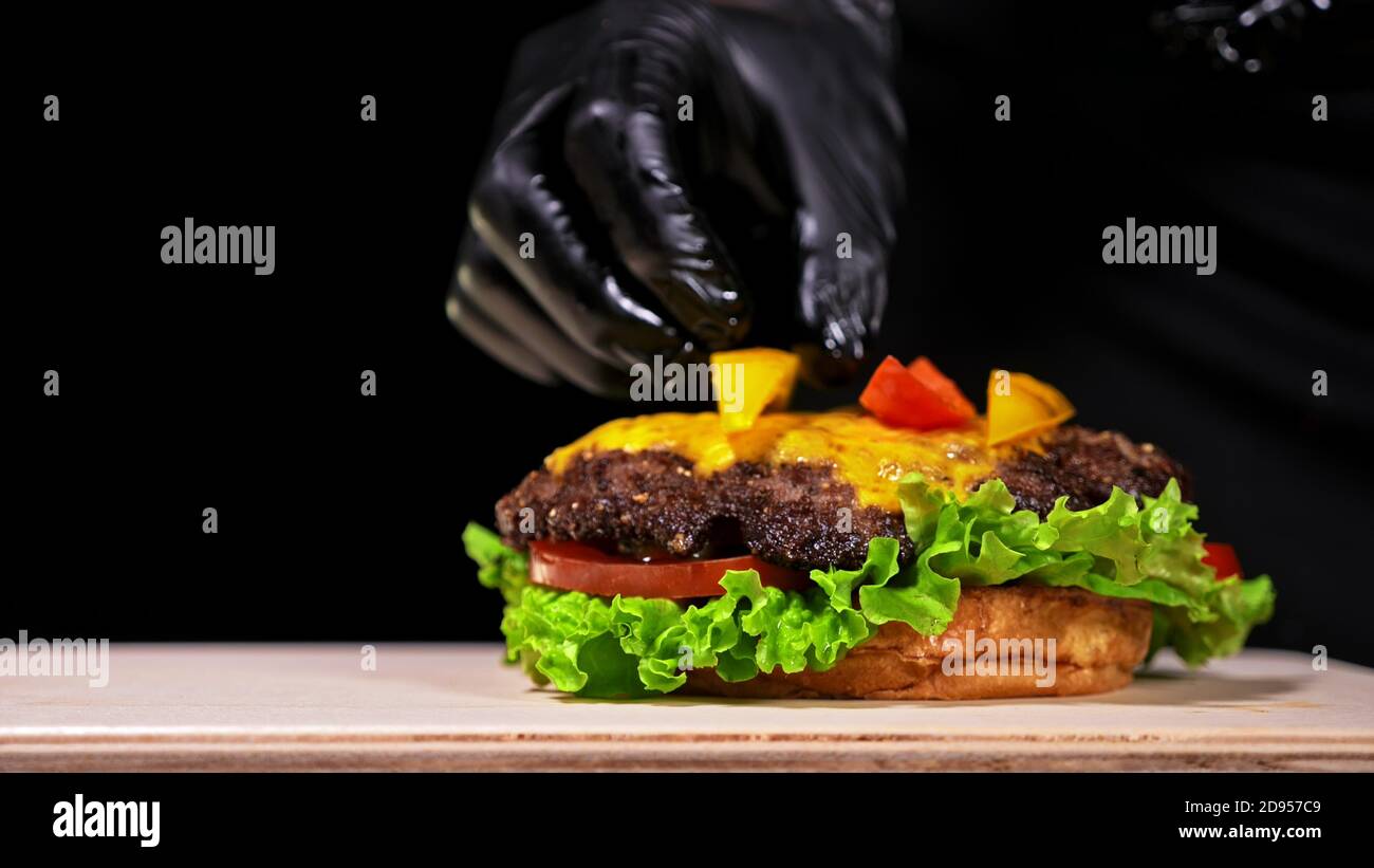 Craft burger is cooking. Consist: red sauce salsa, lettuce, red onion, pickle, cheese, chilli green pepper, air bun and marbled meat beef. Stock Photo